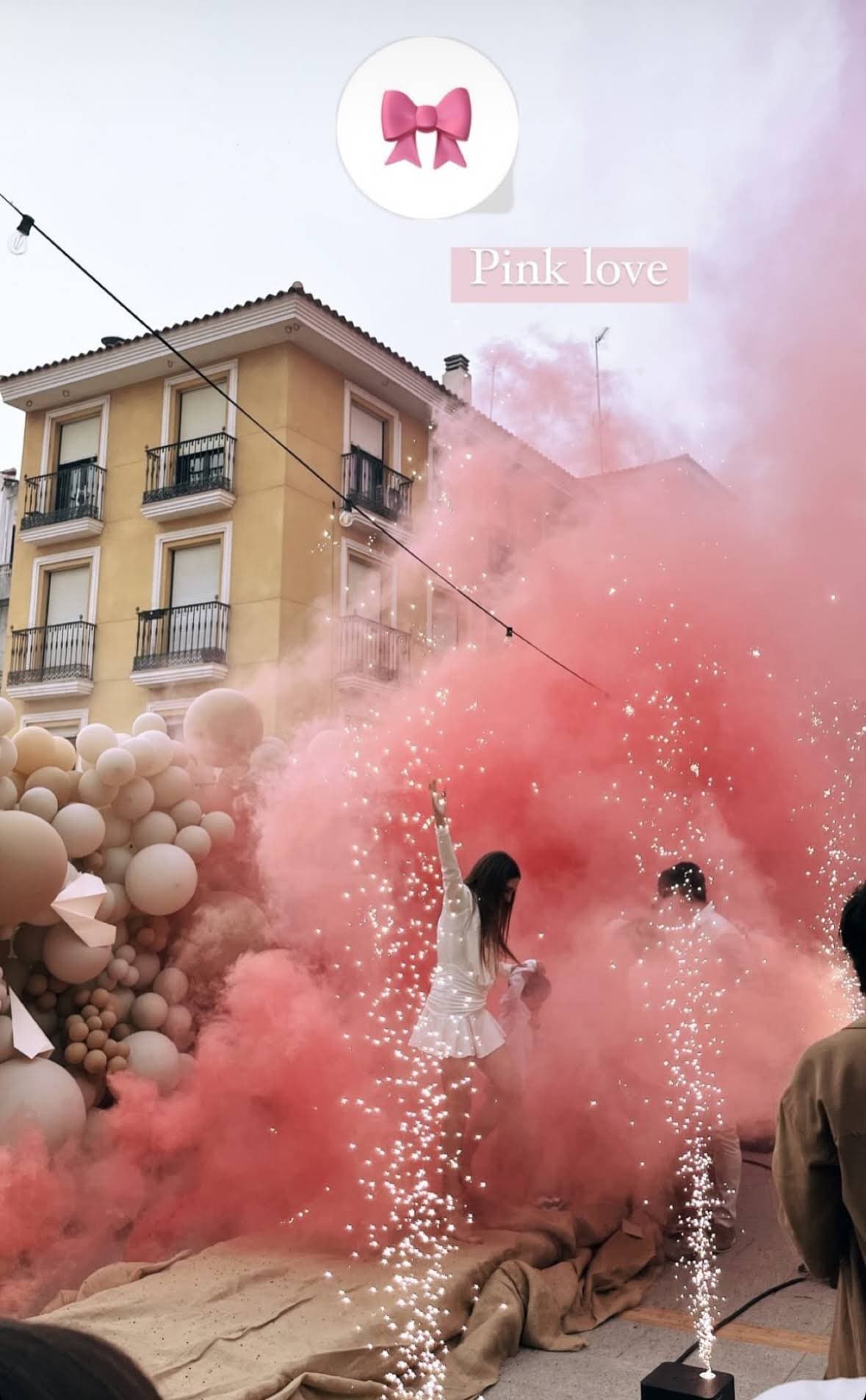 Nube de humo rosa junto a una decoración de globos al aire libre